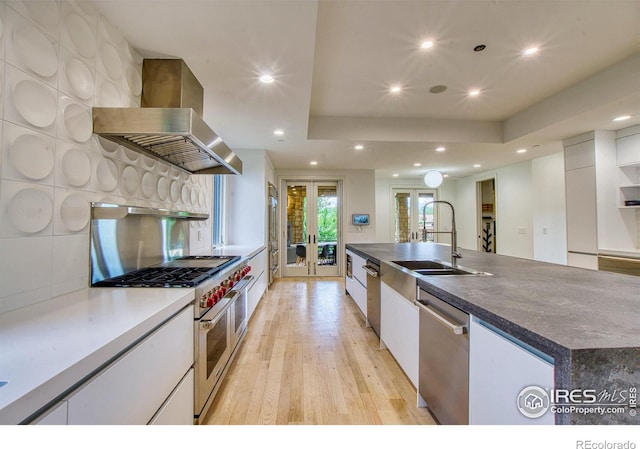 kitchen with white cabinetry, stainless steel appliances, a spacious island, french doors, and wall chimney exhaust hood