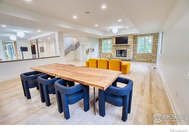 dining room with light hardwood / wood-style floors, a fireplace, and a tray ceiling