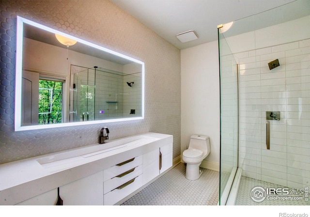 bathroom featuring tile patterned flooring, toilet, tiled shower, and vanity