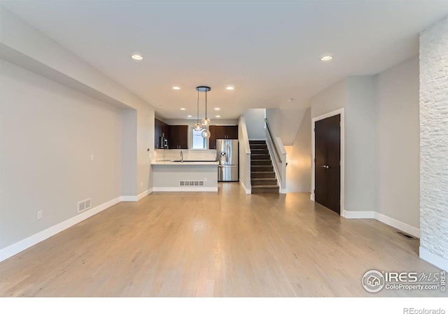 unfurnished living room featuring light wood-type flooring and sink