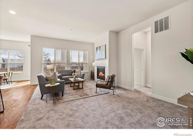 living room featuring light colored carpet and a tiled fireplace