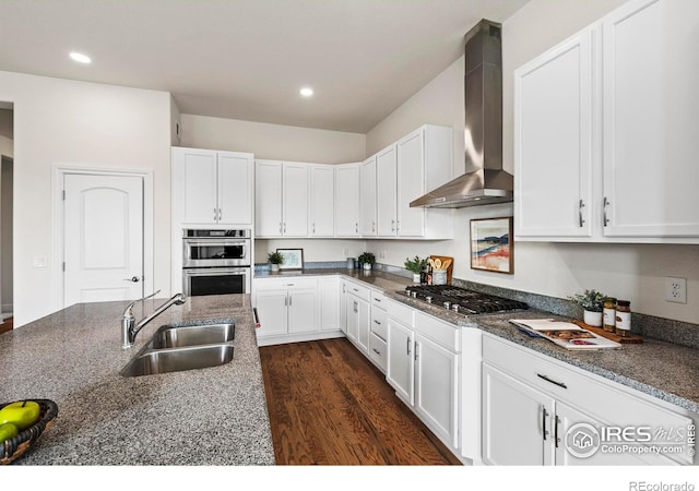 kitchen with sink, wall chimney range hood, dark hardwood / wood-style flooring, white cabinets, and appliances with stainless steel finishes