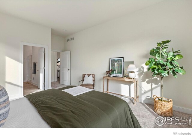 bedroom featuring ensuite bath and light colored carpet