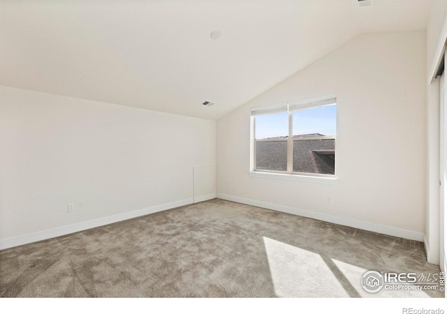 carpeted empty room featuring vaulted ceiling