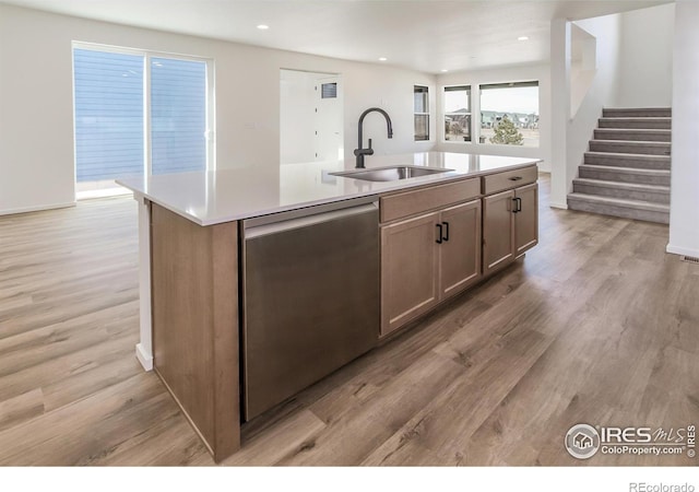 kitchen featuring a sink, a center island with sink, light countertops, and dishwasher