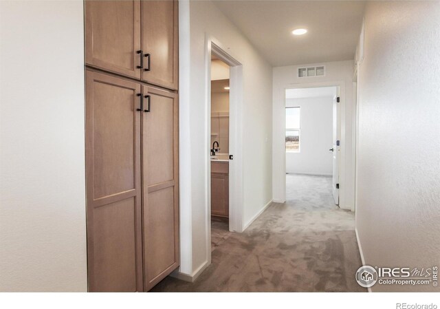 corridor featuring carpet floors, baseboards, and visible vents