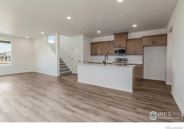 kitchen featuring plenty of natural light, stainless steel microwave, range, and backsplash