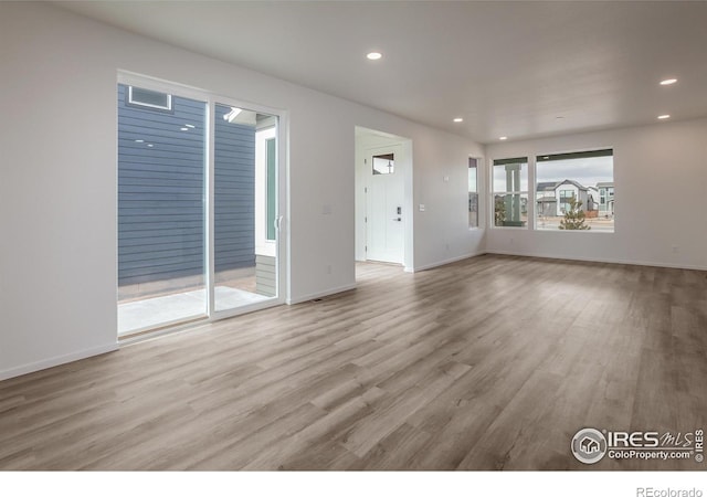 unfurnished living room with baseboards, wood finished floors, and recessed lighting