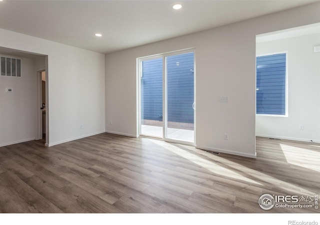 empty room with baseboards, wood finished floors, visible vents, and recessed lighting