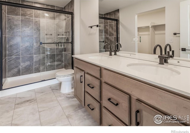 bathroom featuring marble finish floor, a sink, and a shower stall