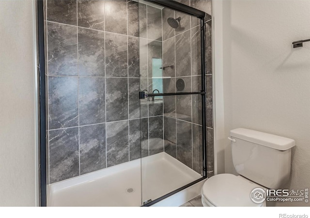 bathroom with a shower stall and toilet