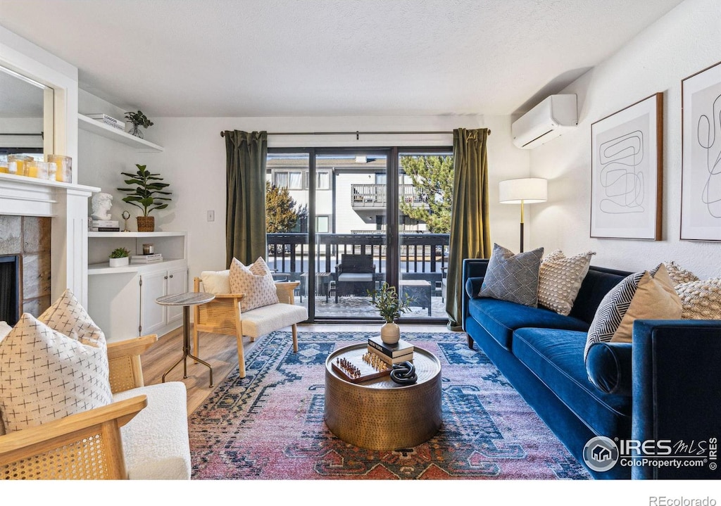 living room featuring a tile fireplace, wood-type flooring, and a wall unit AC