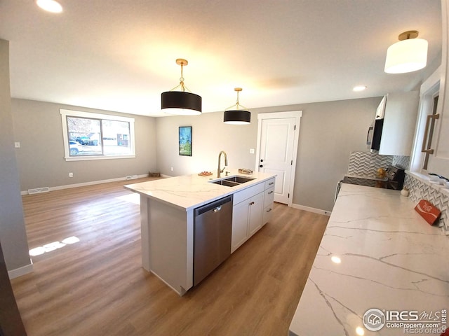 kitchen featuring appliances with stainless steel finishes, a kitchen island with sink, sink, decorative light fixtures, and white cabinets