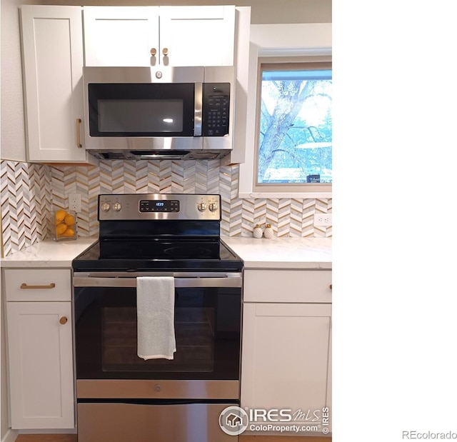 kitchen with decorative backsplash, white cabinets, and appliances with stainless steel finishes