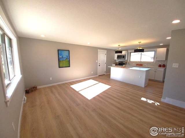 kitchen featuring hanging light fixtures, sink, white cabinets, decorative backsplash, and stainless steel appliances