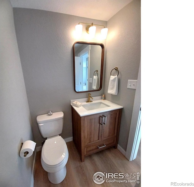 bathroom with hardwood / wood-style flooring, toilet, and vanity