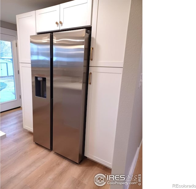 kitchen featuring white cabinets, light hardwood / wood-style flooring, and stainless steel fridge