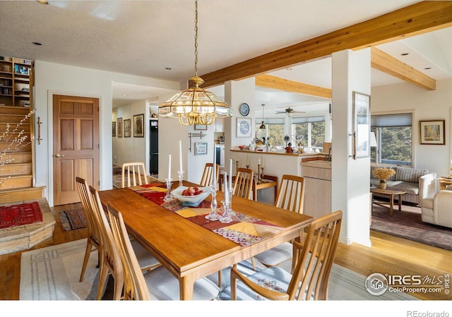 dining area featuring beam ceiling, light wood-type flooring, and an inviting chandelier