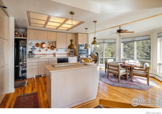 kitchen featuring sink, black appliances, decorative light fixtures, hardwood / wood-style floors, and a center island