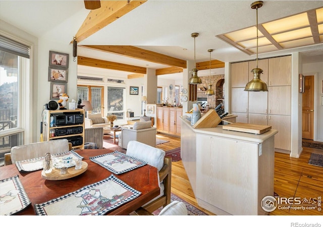 dining area with beam ceiling and light wood-type flooring