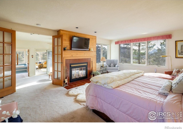 carpeted bedroom featuring french doors and a tiled fireplace