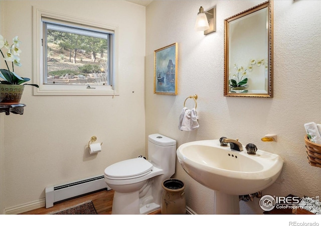 bathroom featuring baseboard heating, sink, hardwood / wood-style floors, and toilet