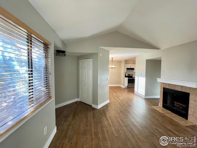 unfurnished living room with hardwood / wood-style floors, lofted ceiling, and a tiled fireplace