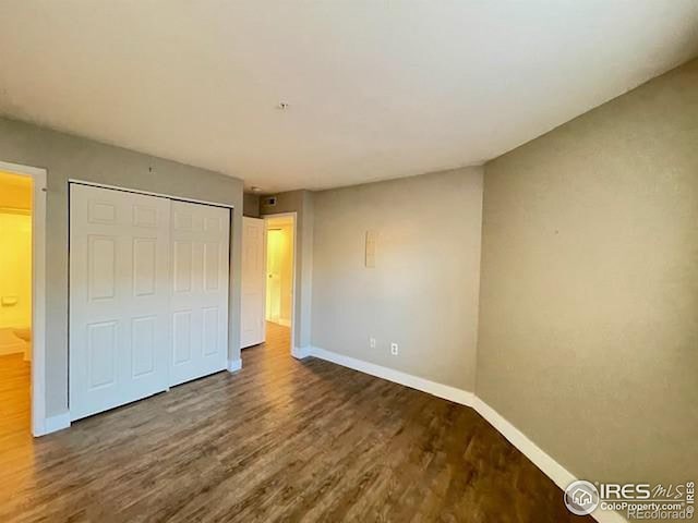 unfurnished bedroom with dark wood-type flooring and a closet