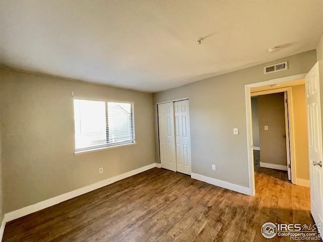 unfurnished bedroom featuring hardwood / wood-style floors and a closet