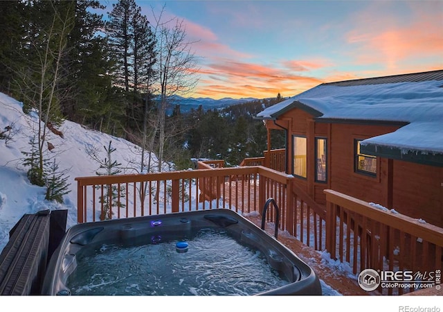 snow covered deck featuring a hot tub and a mountain view