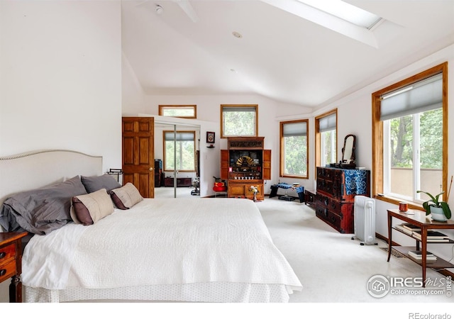 bedroom with radiator heating unit, light colored carpet, multiple windows, and lofted ceiling