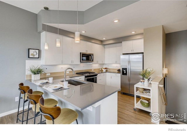 kitchen featuring kitchen peninsula, white cabinetry, hanging light fixtures, and stainless steel appliances