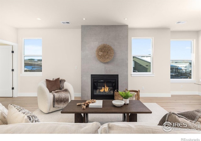 living room featuring light wood-type flooring and a tile fireplace