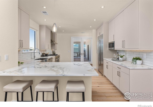 kitchen with white cabinets, light stone countertops, kitchen peninsula, and sink