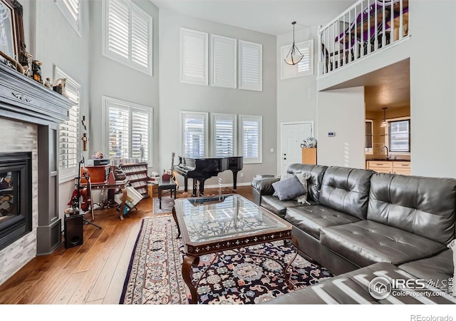 living room with hardwood / wood-style flooring, a towering ceiling, sink, and a tile fireplace