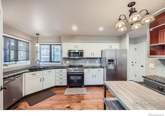 kitchen featuring pendant lighting, white cabinets, stainless steel appliances, and sink