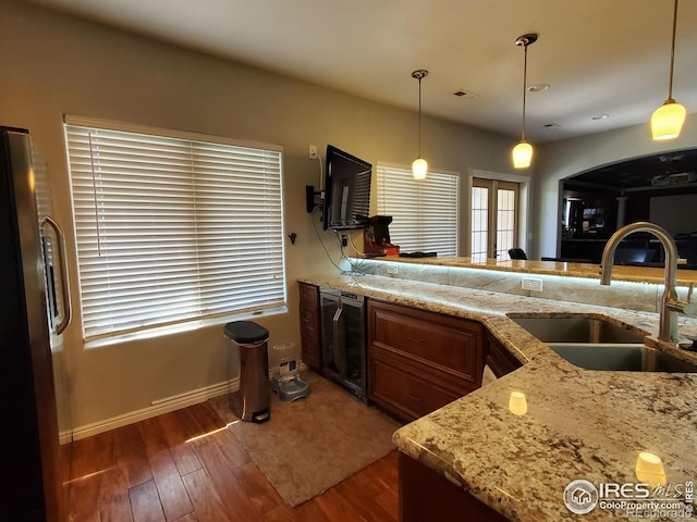 kitchen featuring sink, beverage cooler, pendant lighting, and stainless steel refrigerator with ice dispenser