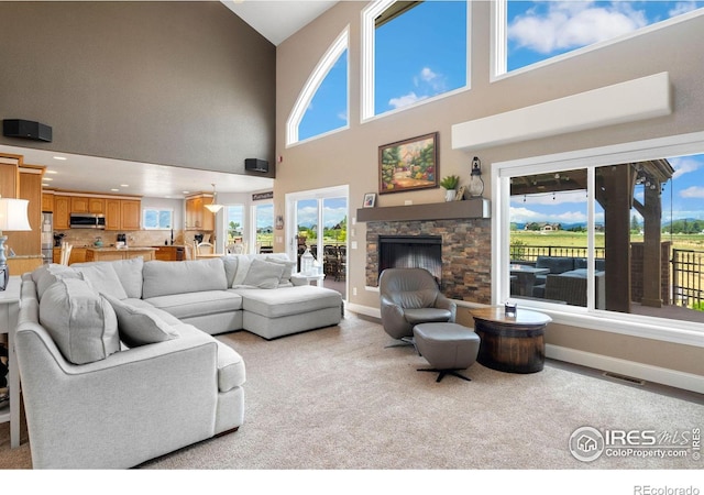 living room featuring a fireplace, high vaulted ceiling, and a healthy amount of sunlight