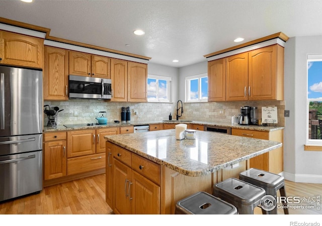 kitchen featuring a wealth of natural light, sink, a kitchen island, and appliances with stainless steel finishes