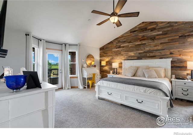 carpeted bedroom with access to outside, wood walls, ceiling fan, and high vaulted ceiling