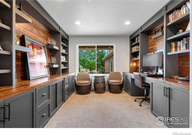 carpeted office space with built in features, built in desk, and a textured ceiling