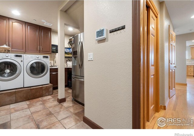 clothes washing area featuring cabinets, washer and clothes dryer, and sink