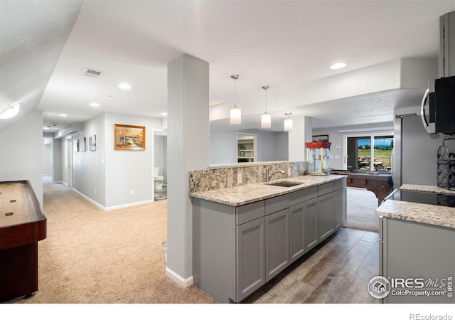 kitchen featuring sink, light stone counters, billiards, pendant lighting, and gray cabinets