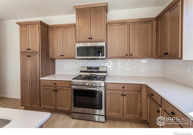 kitchen with decorative backsplash, appliances with stainless steel finishes, and light hardwood / wood-style flooring