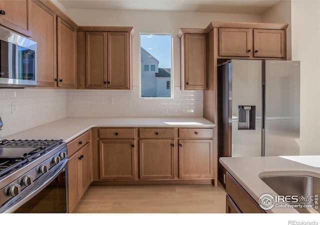 kitchen featuring tasteful backsplash, light hardwood / wood-style flooring, and stainless steel appliances