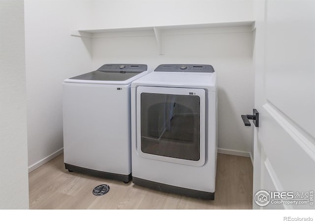 laundry room with washer and clothes dryer and light hardwood / wood-style floors