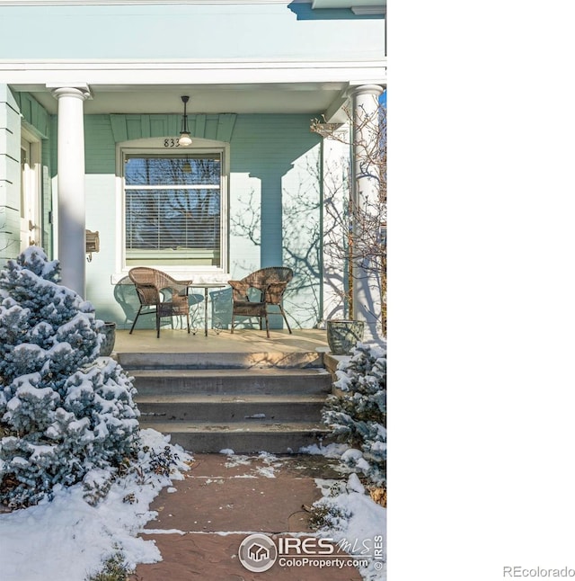 snow covered property entrance with a porch