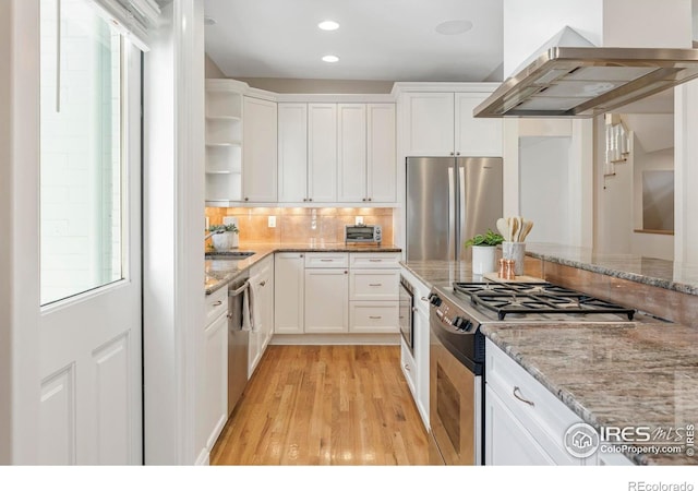 kitchen featuring island range hood, white cabinetry, stainless steel appliances, and light stone counters