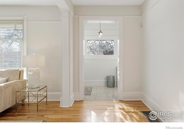 entrance foyer with plenty of natural light, wood-type flooring, and decorative columns