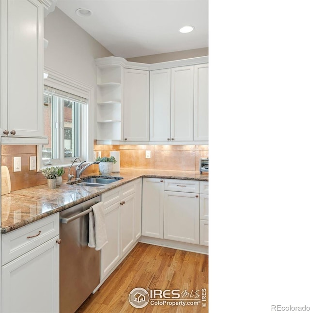 kitchen featuring white cabinets, sink, light hardwood / wood-style flooring, stainless steel dishwasher, and light stone countertops